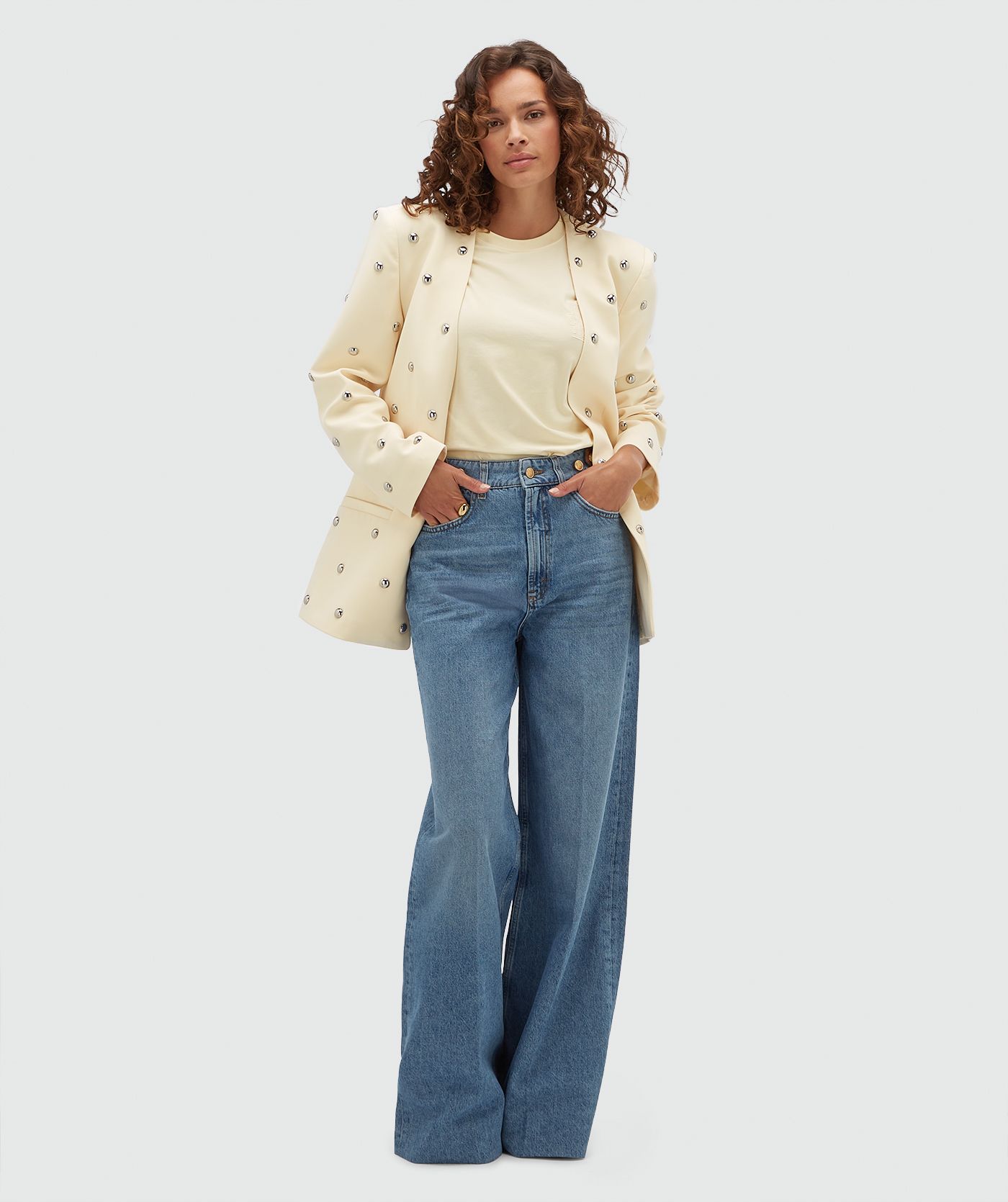 Model draagt lichtgele blazer met zilveren studs.