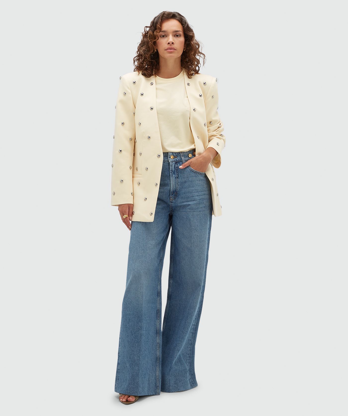 Model draagt lichtgele blazer met zilveren studs.