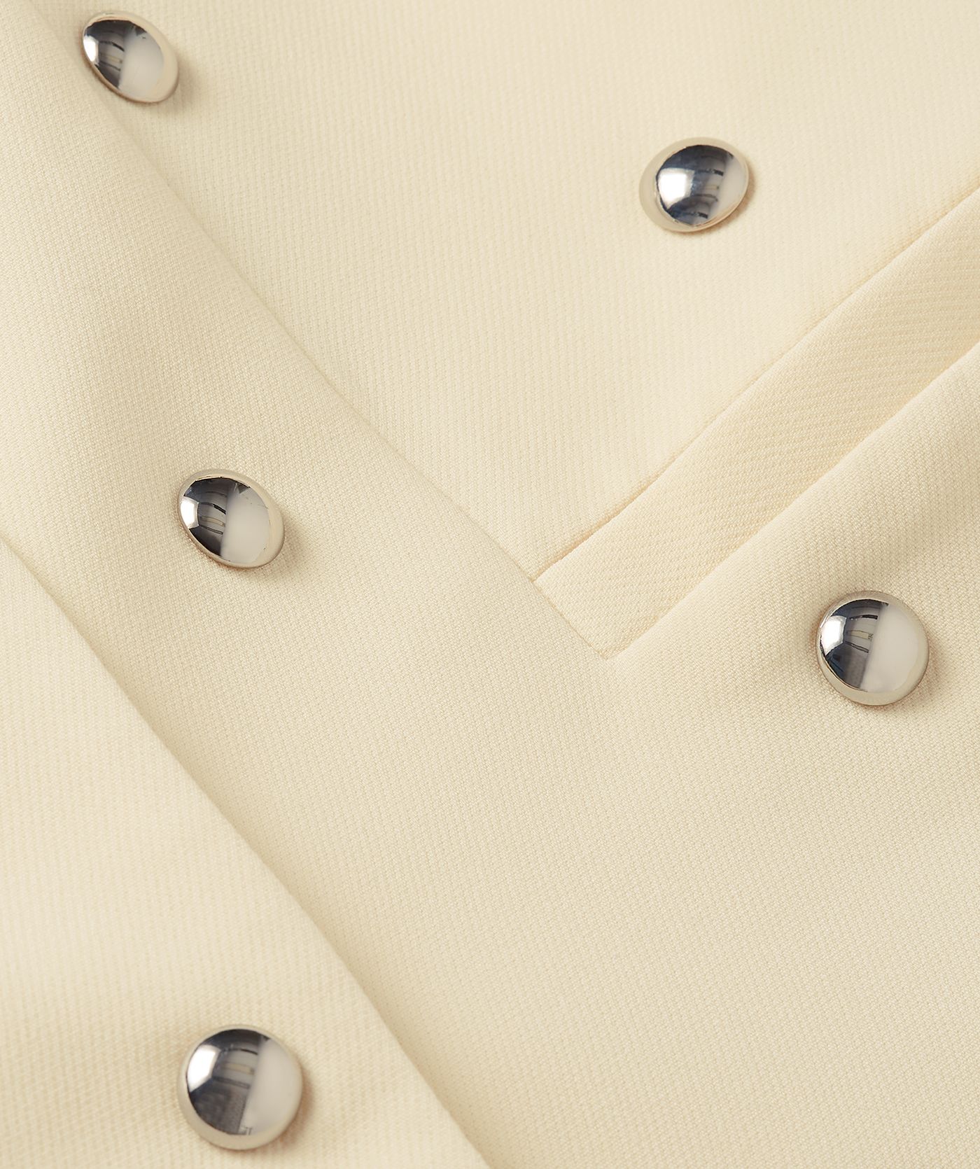 Close-up van de studs die op lichtgele blazer zitten.