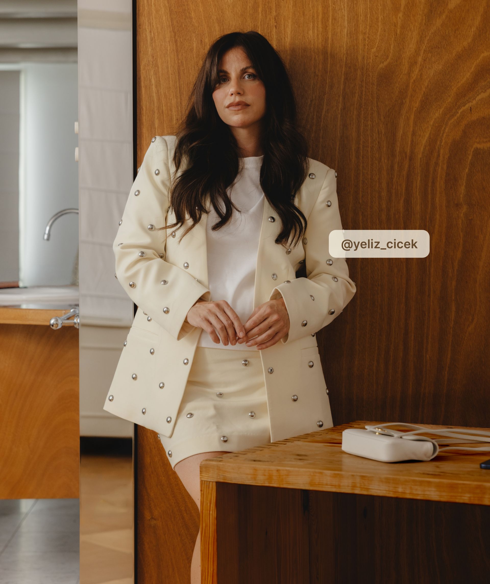 Model staat op straat en draagt lichtgele blazer met zilveren studs met het bijpassende rokje.