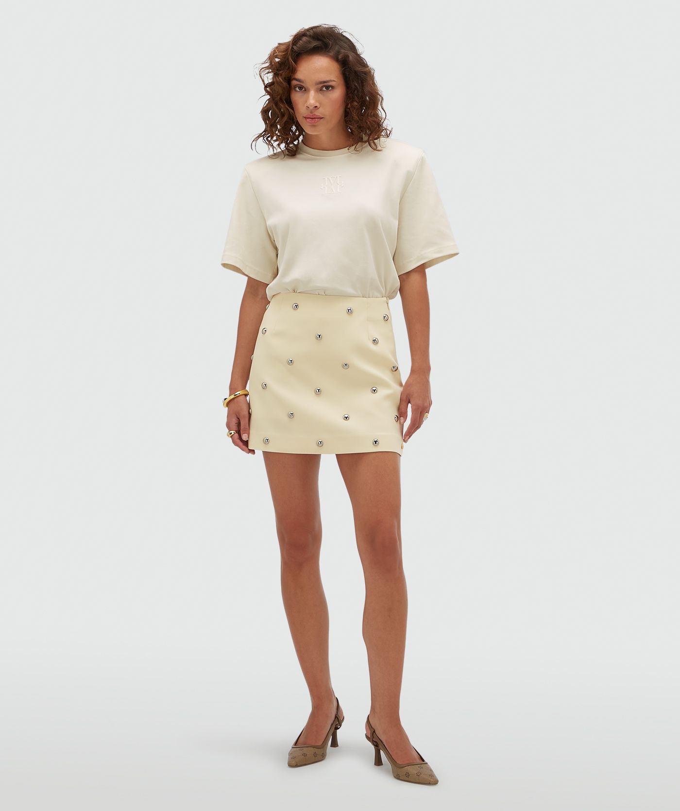 Model draagt een lichtgeel rokje met zilveren studs.