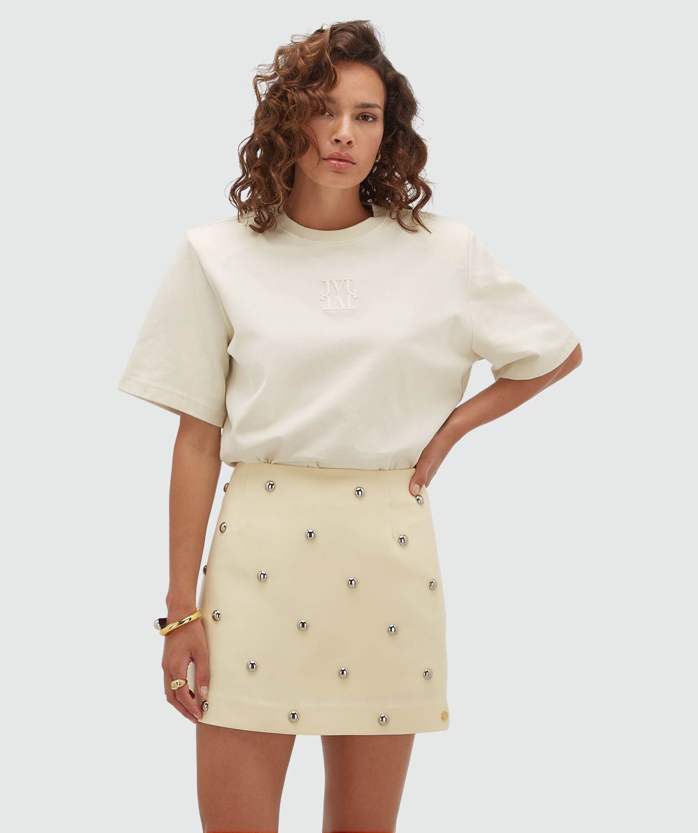 Model draagt een lichtgeel rokje met zilveren studs.