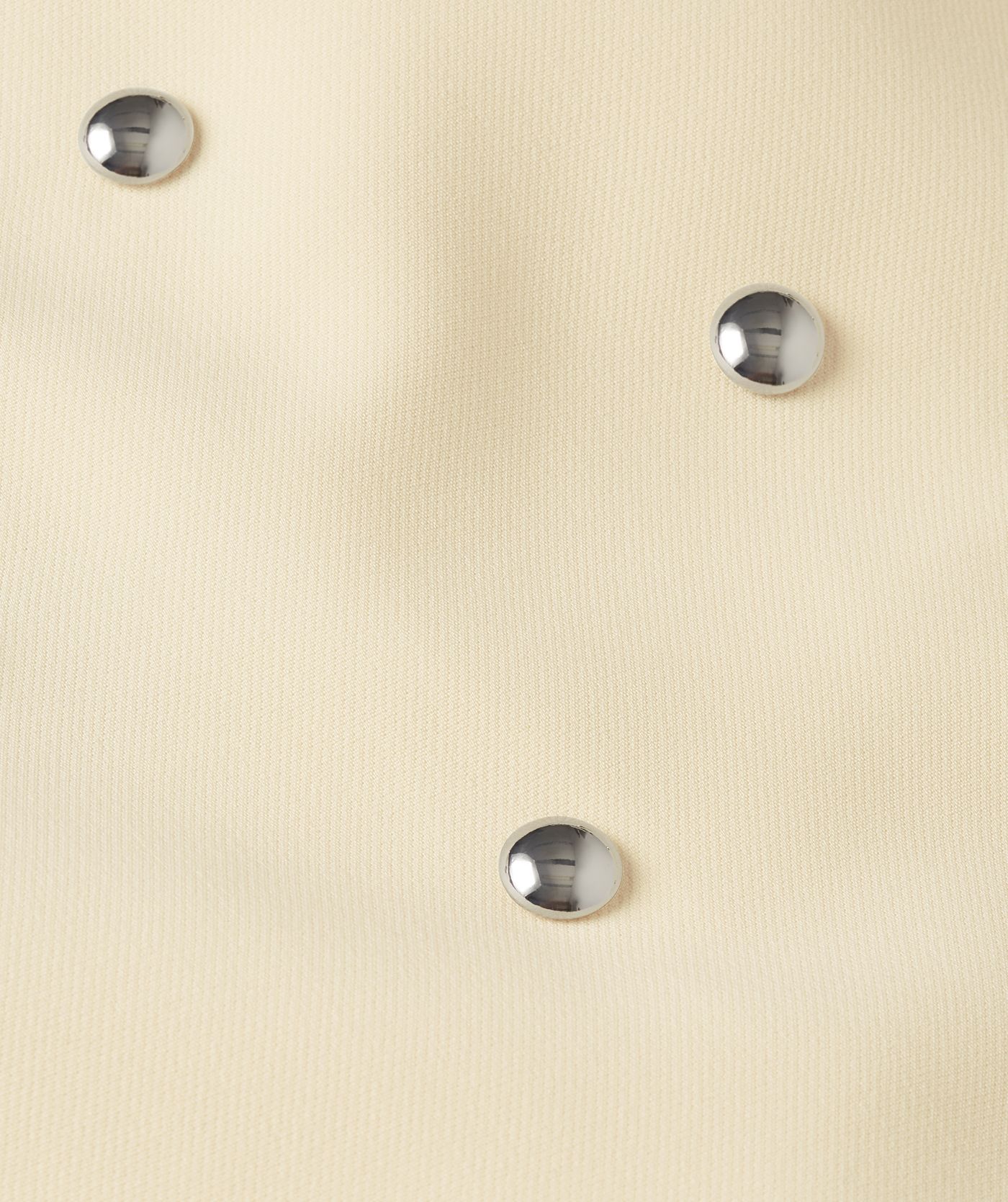 Close-up van de zilveren studs op het lichtgele rokje.