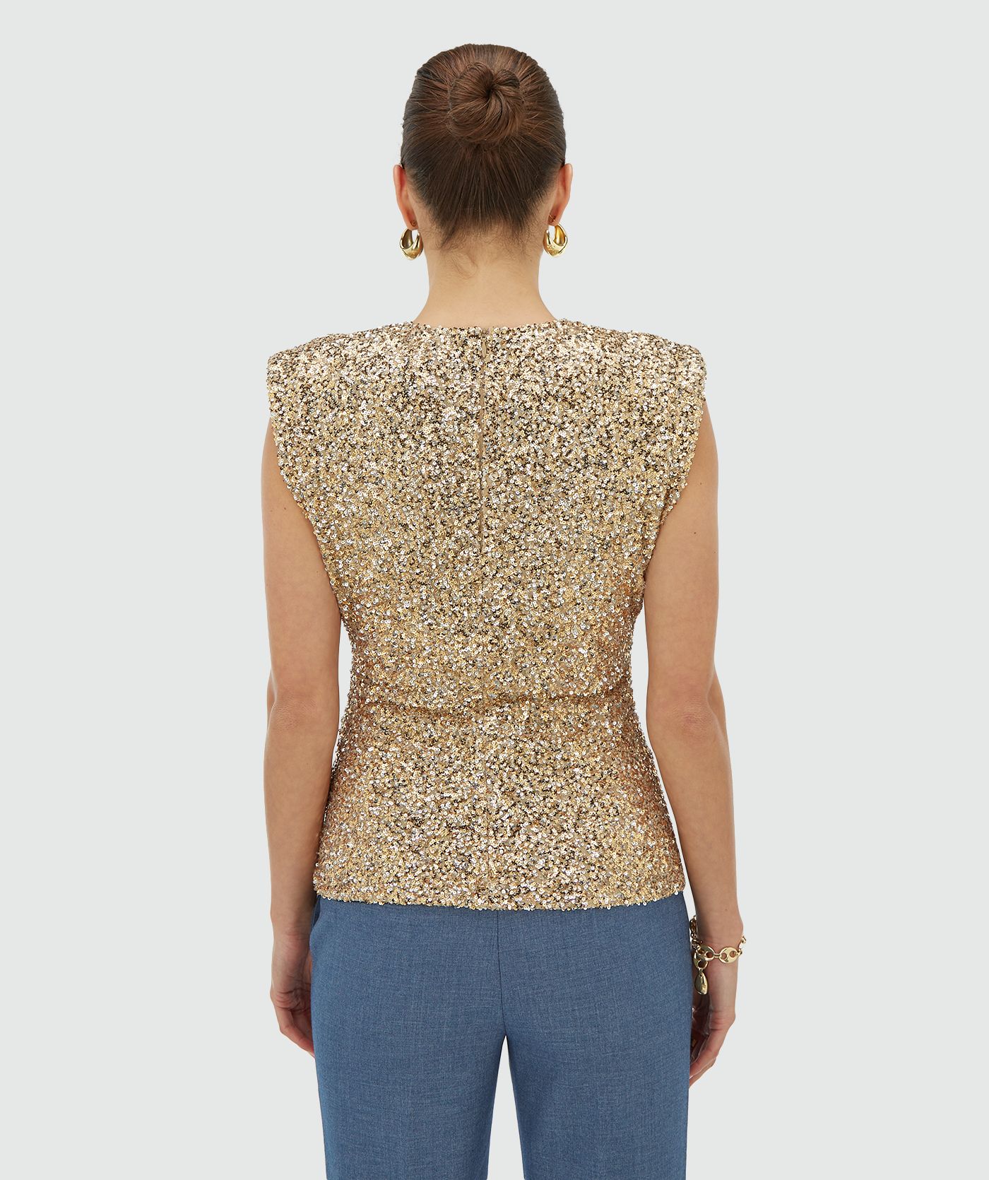 Achteraanzicht van een model in een mouwloze goud zilver pailletten top met schoudervulling - JOSH V
