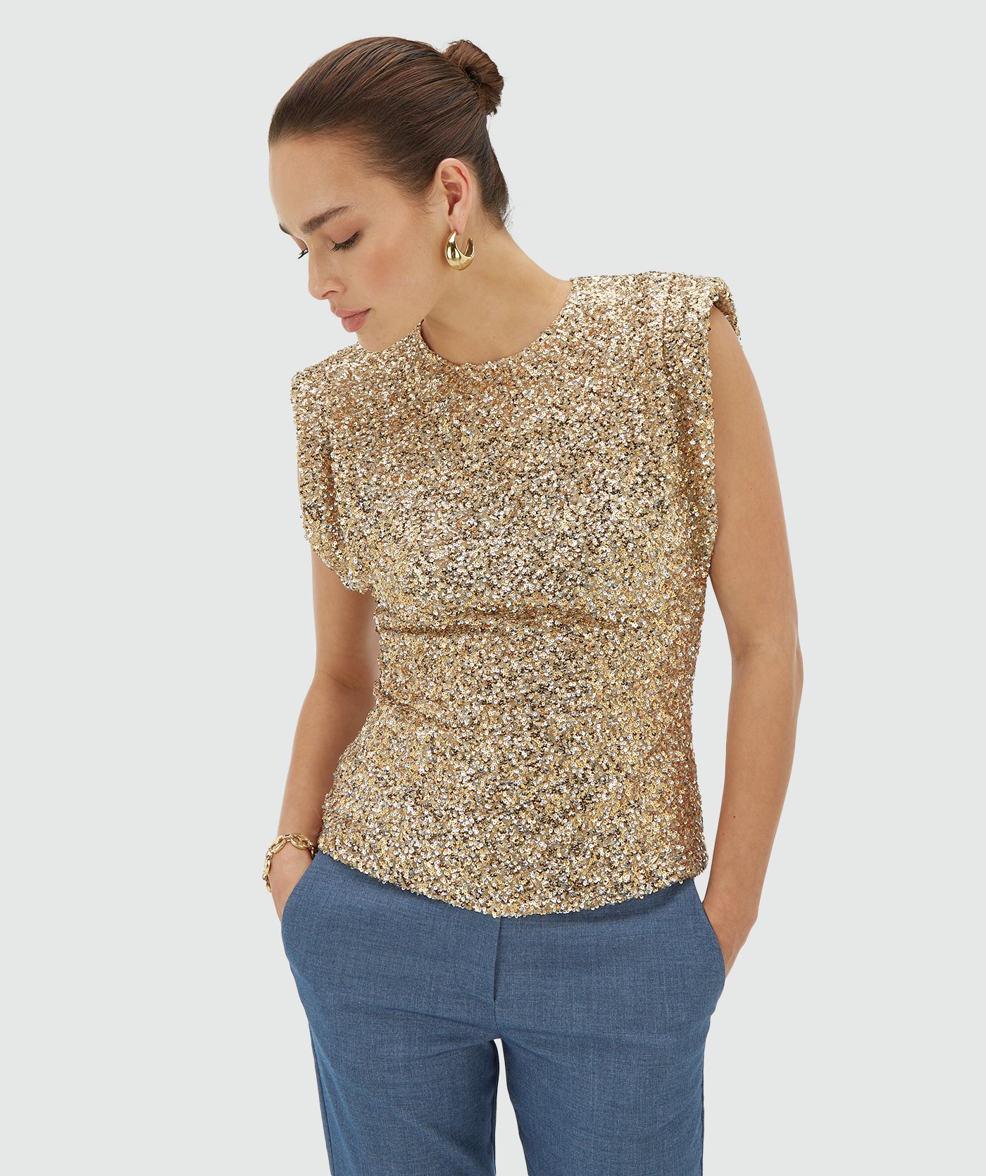 Model draagt een mouwloze goud zilver pailletten top met schoudervulling - JOSH V
