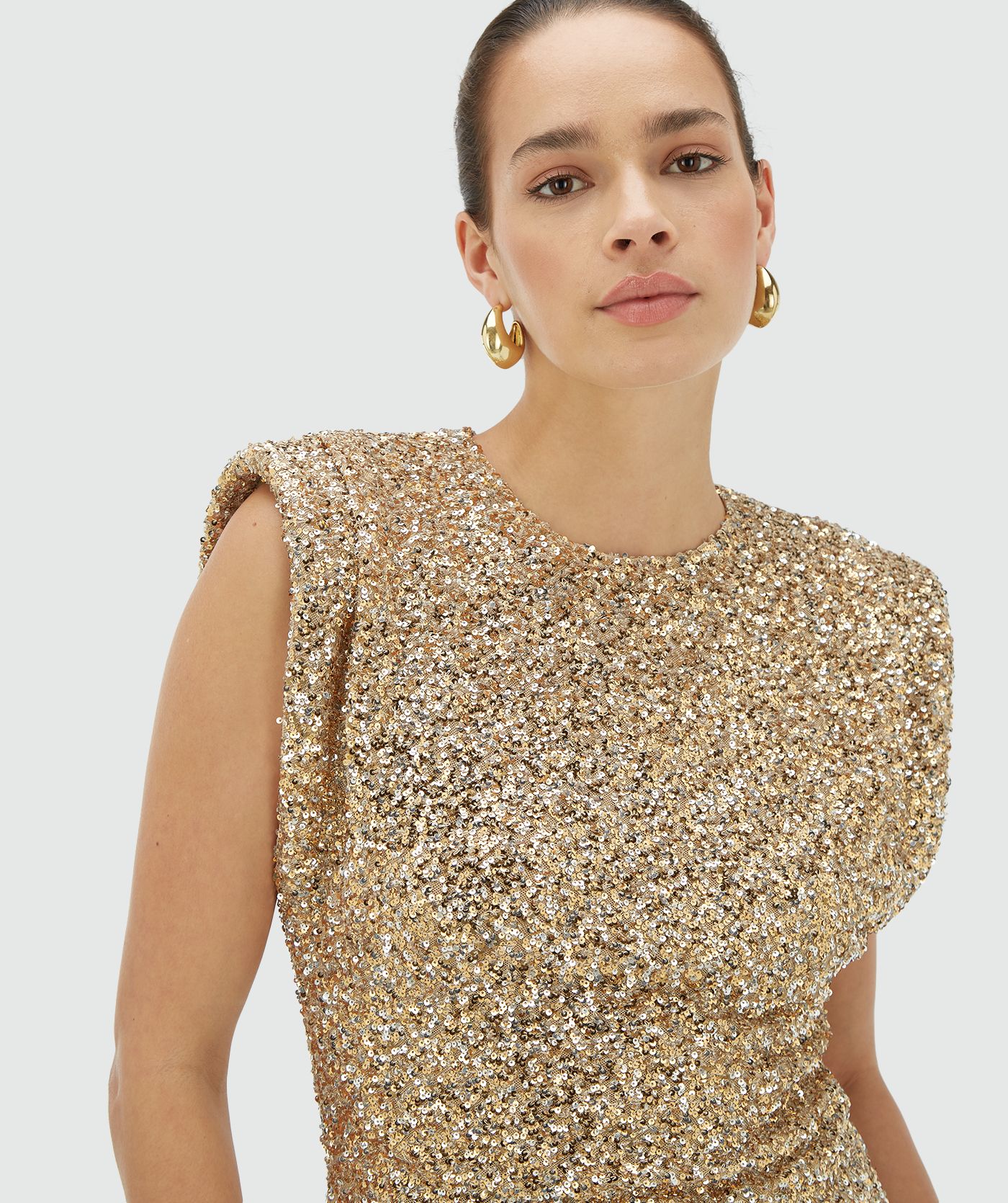 Model draagt een mouwloze goud zilver pailletten top met schoudervulling - JOSH V